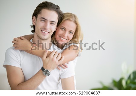 Young happy woman piggybacking her handsome boyfriend. Portrait of cheerful casual people in love, students having hopes, dreams, goals, bride and groom with family wants and aspirations