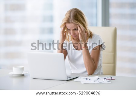 Young attractive woman at modern office desk, working on laptop, massaging temples to forget about constant headaches, noisy loud office giving a migraine, relieving stress, chronic pain, help soothe