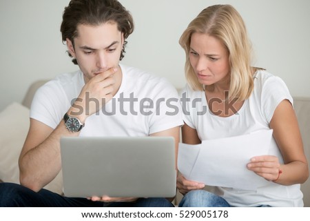 Young man and woman working with laptop, holding documents, using online mortgage calculator to save money on home loan, applying for visa, mother and son choosing educational program, checking test
