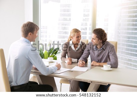 Young couple in love starting family life, applying for mortgage to buy accommodation, purchasing, renting new apartment, meeting with real estate agent, signing loan contract, choosing place to live