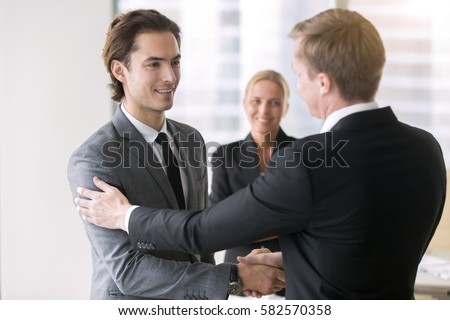 Boss promoting young subordinate. Two businessmen handshaking, congratulating on promotion, ensure long-term prosperity, human resource solutions, hired effective team, advancement of company position