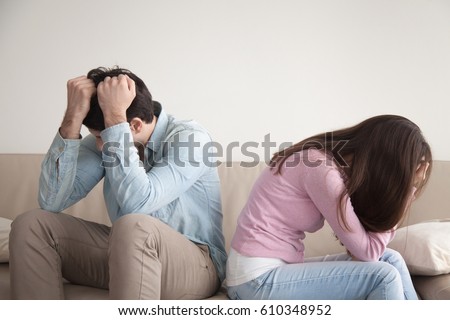 Man and woman feeling stressed and angry at each other, frustrated couple sitting back to back, hands on head, not talking after dispute, teenagers quarrel, family crisis and relationships problems