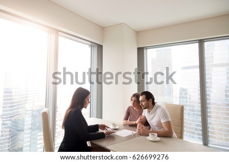 Young family couple meeting with bank worker to sign loan contract, discussing banking credit, personal insurance or mortgage investment, manager showing clients build project on tablet