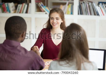 Smiling confident female applicant shaking hand of african hr manager making good first impression, employer congratulates attractive happy woman candidate getting hired, employment handshake concept