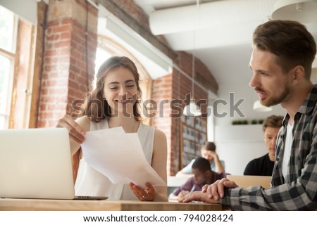 Businesswoman discussing business documents at meeting with client customer in shared office, smiling woman employee helping mentoring young man intern explaining corporate paperwork in co-working