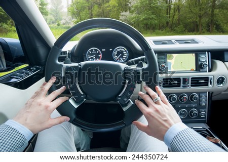 Man in suit driving luxury offroad car in the forest using GPS.