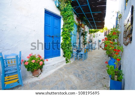 Traditional greek blue blinds and chairs on a small back street