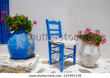 Traditional greek blue chair together with flower pots