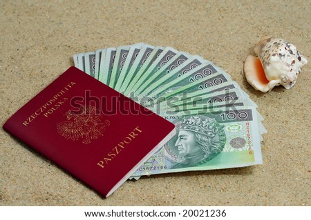 Passport stuffed with polish money with a shell on sand