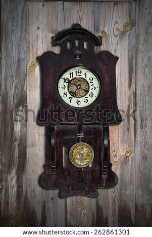 old pendulum clock on the background of wooden wall