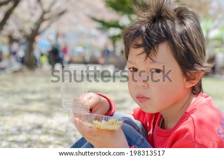Cute boy eating fries on the nature