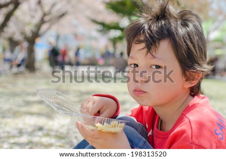 Cute boy eating fries on the nature
