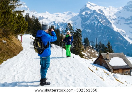 Man photographing woman against the backdrop of the Alps.
