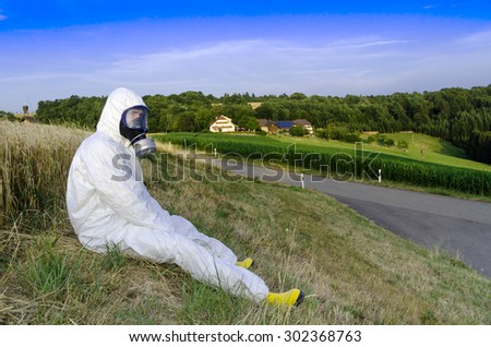 A man in a protective suit and gas mask on the background of nature. Ecology.