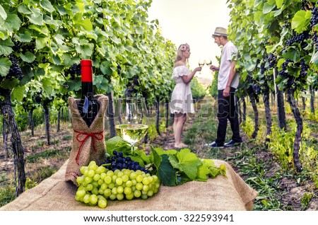 Bottle of wine, glasses of wine and grapes on the background of couple in love. Romantic evening.