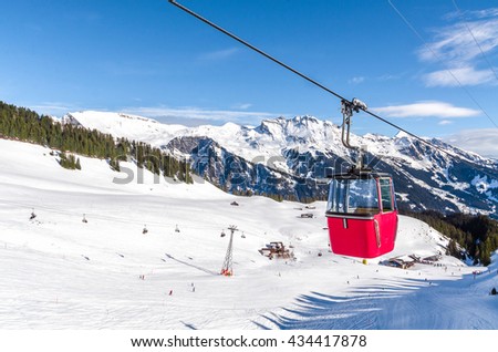 ski slope in Swiss Alps in sunny day. Red cable car above and mountains behind, skiing resort, Switzerland.