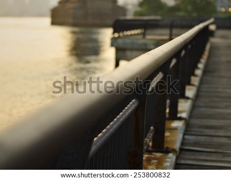 A photograph of a railing on the wooden walking path in Brooklyn Bridge Park that leads to the Manhattan Bridge.