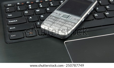 Telemarketing and remote work set: Laptop (notebook) and cell phone on the keyboard.