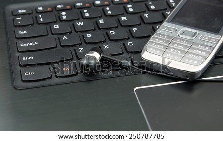 Telemarketing, remote work, voip set: Laptop (notebook), headphones and cell phone on the keyboard.