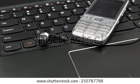 Telemarketing and remote work set: Laptop (notebook), headphones and cell phone on the keyboard.
