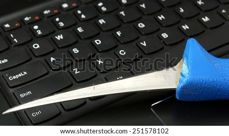 Digital, internet fraud, phising: blue kitchen knife on the laptop keyboard