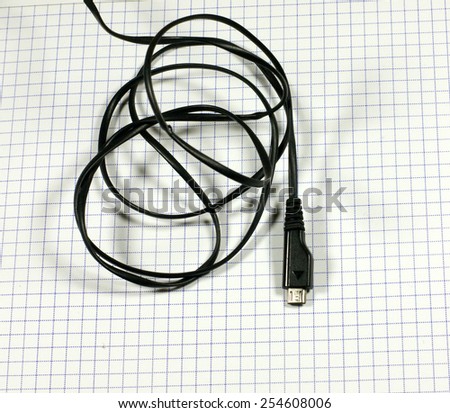 Mobile, cell phone charger cable on the notebook grid
