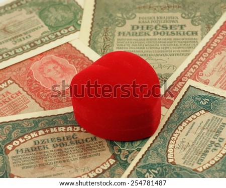 Old love: red heart shaped jewelery box on old, historical Polish notes, bills from Second World War. Focus on some part of the image only - rest is blur by intention.