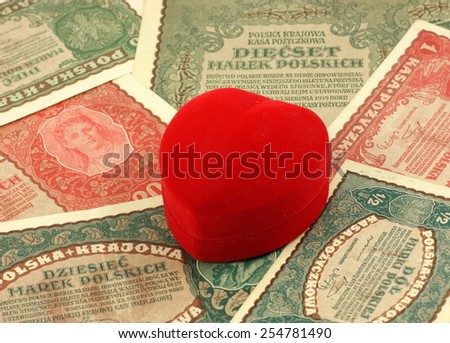 Old love: red heart shaped jewelery box on old, historical Polish notes, bills from Second World War.