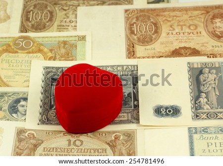 Old love: red heart shaped jewelery box on old, historical Polish notes, bills from Second World War. Focus on some part of the image only - rest is blur by intention.