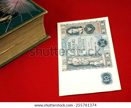 Historical, old Polish notes, bills (1919 - 1940) on the red carpet background next to the old book. Focus on some part of the image only, rest is blur by intention.
