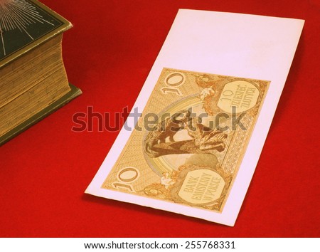 Historical, old Polish notes (1919 - 1940), bills on the red carpet background next to old book - classic photo style, focus on some part of the image only.