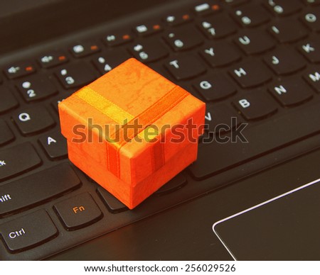e-commerce and web shopping: orange present case on the laptop keyboard - classic style