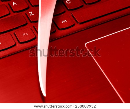 Internet crime: sharp knife on the laptop keyboard in red filter