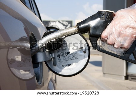Close up of hand with gloves using petrol pump and filling Diesel / Fuel on her car