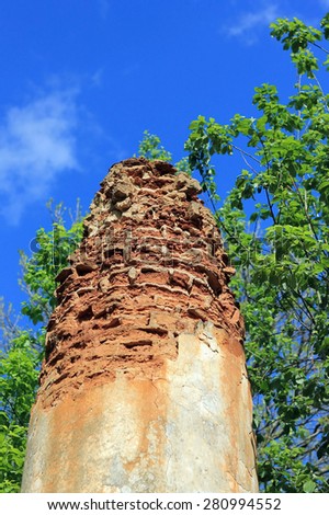 Old column of abandoned church in forest on trees and sky background