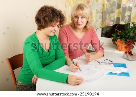 Adult blond woman and young woman signing documents