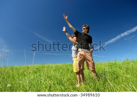 Young man and woman pointing their future on green field