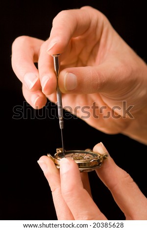 Watch-maker repairing old abraded watch isolated on black background