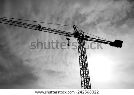Construction crane bottom view in operation with cloud sky background. Black&White photo.