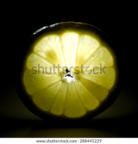 Slice of lemon on a black background. Back light.