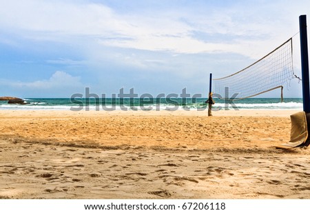 Court side view of a beach volleyball venue with a crashing waves in the background