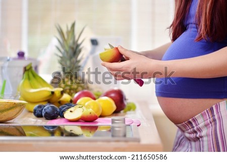 pregnant woman peeling an apple