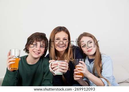Mom with your two sons drinking juice in the breakfast