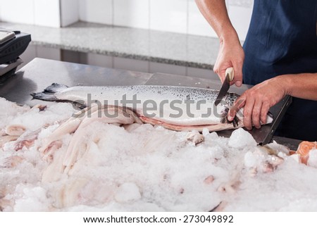 Man cutting a pink salmon on the table