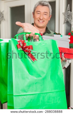 Man holding a green giftbag with a red bun