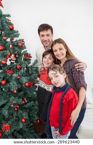 Happy family smiling beside the christmas tree