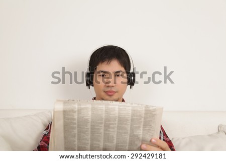 Man listening to music and reading the newspaper