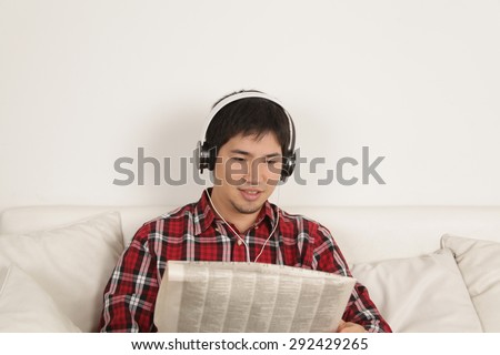 Man listening to music and reading the newspaper
