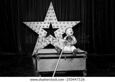 black and white, little girl sitting on the box and singing into a microphone