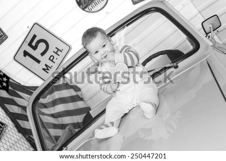 black and white, European little girl sitting on the green hood of the car